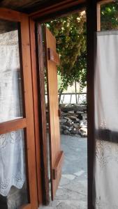 une porte ouverte avec une fenêtre et un rideau dans l'établissement Eleni's Cottage, à Apsiou