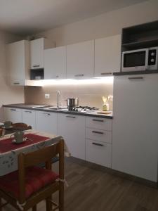 a kitchen with white cabinets and a stove top oven at Appartamento Verdebleu - Lago e Terme in Levico Terme