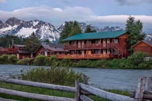 a large wooden house with mountains in the background at Redfish Riverside Inn in Stanley