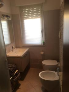 un bagno con un water, un lavandino e una finestra di apartmentsIT via Verona 16 ad Alba Adriatica