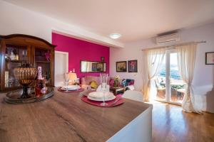 a living room with a dining room table with a pink wall at Maja Apartment Cavtat II in Cavtat
