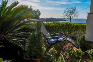 a chair in a garden with plants and flowers at Maja Apartment Cavtat II in Cavtat