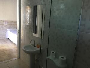 a bathroom with a sink and a glass shower at Pousada Poleto's in Bertioga