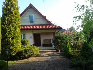 Biały dom z czerwonym dachem i podjazdem w obiekcie Dom na Skarpie w mieście Wierzbica