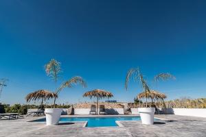 una piscina con sombrillas y sillas de paja y una piscina en Casa La Vuelta, en Formentera de Segura