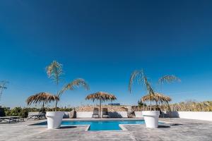 una piscina con ombrelloni e sedie di paglia e una piscina di Casa La Vuelta a Formentera de Segura