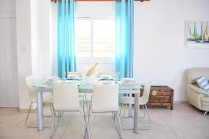 a dining room with a blue table and white chairs at Sol y Mar Malama Villa in Paralimni