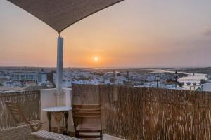 d'un balcon avec des chaises et un coucher de soleil en arrière-plan. dans l'établissement Tavira Apartment, à Tavira