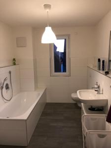 a white bathroom with a tub and a sink at Fewo Dani in Rheinhausen