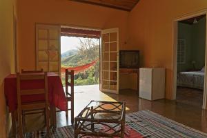 ein Wohnzimmer mit einem Tisch und einem TV sowie ein Zimmer mit einem Bett in der Unterkunft Pousada Dona Felicidade in Cunha + 82 Fotos