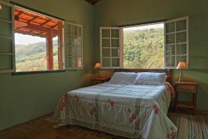ein Schlafzimmer mit einem Bett und zwei Fenstern in der Unterkunft Pousada Dona Felicidade in Cunha