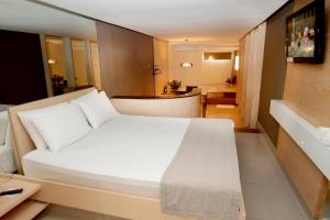 a bedroom with a large white bed and a bathroom at Raru's Motel Via Costeira (Adult Only) in Natal