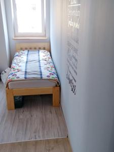 małe łóżko w pokoju z oknem w obiekcie Apartament w Karkonoszach w mieście Podgórzyn