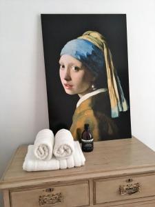 a painting of a woman in a headdress on a dresser with towels at NineT7 in Tilburg