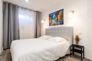 - une chambre avec un lit blanc et une peinture murale dans l'établissement CityCosy Strasbourg - T2 Hirtz Orangerie, à Strasbourg