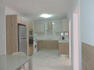 una cocina con electrodomésticos blancos y armarios de madera en Antros, Apartment 1 en Xlendi
