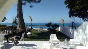 una mujer sentada en una silla en un patio cerca de la playa en Villa a Diamante Sulla Spiaggia, en Belvedere Marittimo