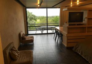 a living room with a television and a table with chairs at Lofts - Club de campo San Pedro in San Pedro