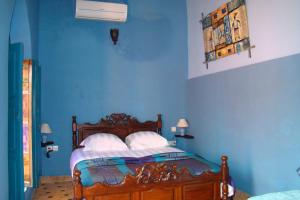 a bedroom with blue walls and a bed with white pillows at Riad Menthe Et Citron in Meknès