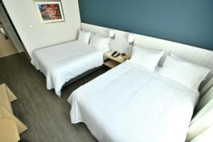 2 camas en una habitación de hotel con sábanas blancas en Holiday Inn Express Asuncion Aviadores , an IHG Hotel, en Asunción