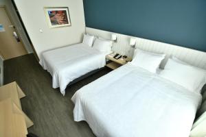 two beds in a hotel room with white sheets at Holiday Inn Express Asuncion Aviadores , an IHG Hotel in Asuncion