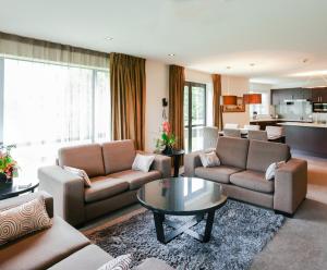 a living room with couches and a coffee table at Village Lake Apartments in Hanmer Springs