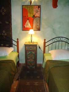 a bedroom with two beds and a lamp on a table at Riad Menthe Et Citron in Meknès