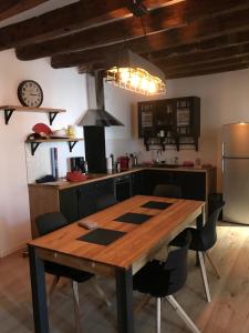 a kitchen with a wooden table with chairs and a refrigerator at le logis de l’étoile in Nîmes