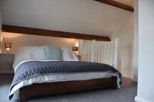 een slaapkamer met een groot bed met witte lakens en blauwe kussens bij The Hayloft Cottage in Whitby