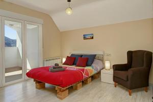 een slaapkamer met een bed met een rode deken en een stoel bij Ático con chimenea en Sierra Nevada-Güejar Sierra in Güéjar-Sierra