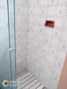 y baño de azulejos blancos con ducha y banco. en Hotel Central Rosário en Jundiaí