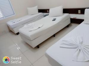 two beds in a room with white furniture at Hotel Central Rosário in Jundiaí +5 photos