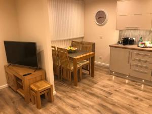 a kitchen with a table and a tv and a table and chairs at exploreNESS Apartment in Inverness