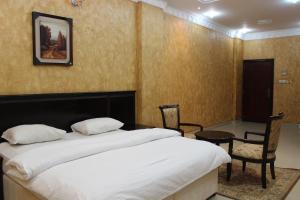 تاج الخليج للشقق الفندقية في سيب: غرفة نوم بسرير وطاولة وكراسي