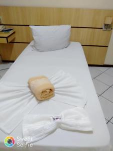 Una cama blanca con una camisa blanca y un sombrero. en Hotel Central Rosário en Jundiaí