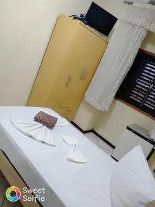 a room with a white bed and a yellow door at Hotel Central Rosário in Jundiaí