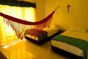 a bedroom with two beds and a hammock in it at Hostal Cultural El Telar in San Jacinto