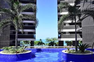 uma piscina com duas palmeiras em frente a um edifício em Grupo Vip Landscape Fortaleza em Fortaleza