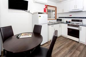 uma cozinha com mesa e cadeiras e uma cozinha com armários brancos em Ingenia Holidays Torquay Australia em Torquay
