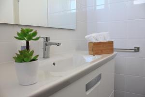 uma casa de banho branca com um lavatório e um espelho em Casa do Kiko em Ponta Delgada