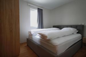 a bedroom with a bed with white sheets and a window at Selfell Guesthouse by Stay Iceland in Kálfafell