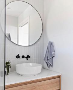 La salle de bains est pourvue d'un lavabo blanc et d'un miroir. dans l'établissement Swell Kiama, à Kiama