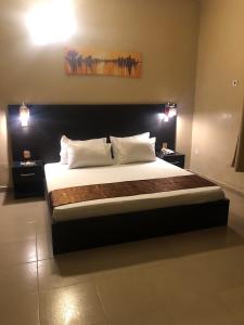 a bedroom with a large bed with two lights at Posh Apartments Business Hotel in Ikeja