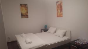 1 cama con sábanas blancas y almohadas en una habitación en Ubytovanie - súkromie v meste (2), en Bratislava