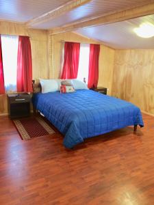1 dormitorio con cama azul y cortinas rojas en Hostal Host Patagonia en Punta Arenas