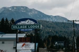 ein Schild für eine Dorflodge vor einem Berg in der Unterkunft Golden Village Lodge in Golden