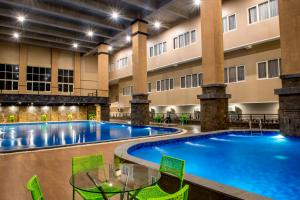 an indoor pool in a hotel with tables and chairs at Grand Padis Hotel in Bondowoso