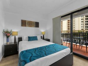 a bedroom with a large bed and a balcony at Central Brunswick Apartment Hotel in Brisbane