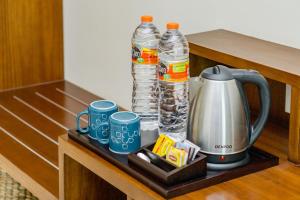 a counter with a tea kettle and cups of water at Anja Jimbaran in Jimbaran