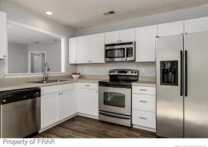 a kitchen with white cabinets and stainless steel appliances at Cozy cottage feel, 5 mins from Ft. Bragg in Fayetteville